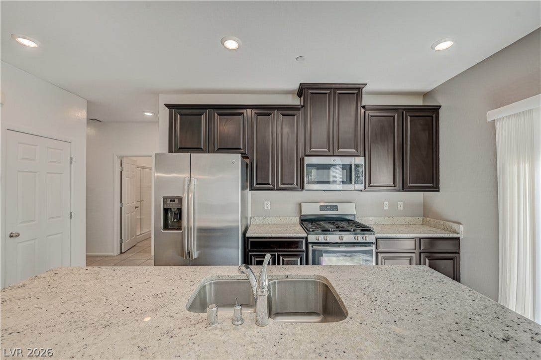 2455 Sunflower Days Avenue, #1056, North Las Vegas, NV 89031 Gleaming stone countertops and rich dark cabinetry highlight this modern cooking space.
