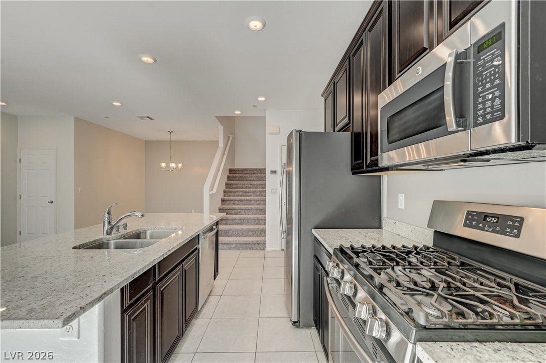 2455 Sunflower Days Avenue, #1056, North Las Vegas, NV 89031 Rich dark cabinetry and stone countertops anchor this modern, light-filled kitchen space.