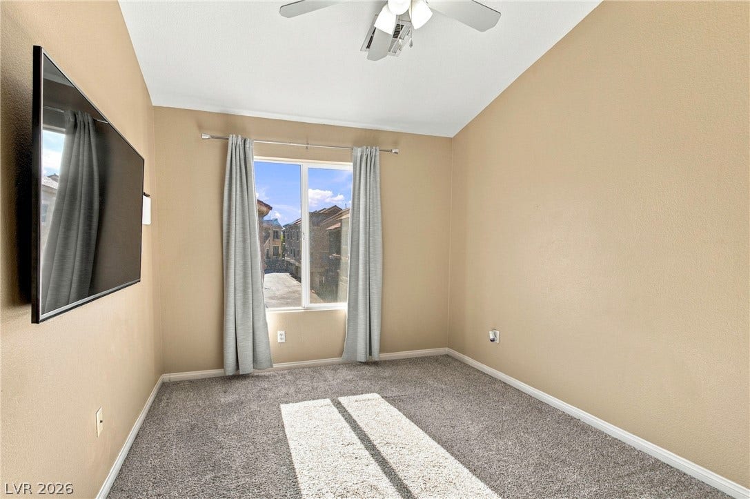 2752 Fountain Vista Lane, Henderson, NV 89074 Sunlight streams through a large window, highlighting the vaulted ceiling and carpeted floor.