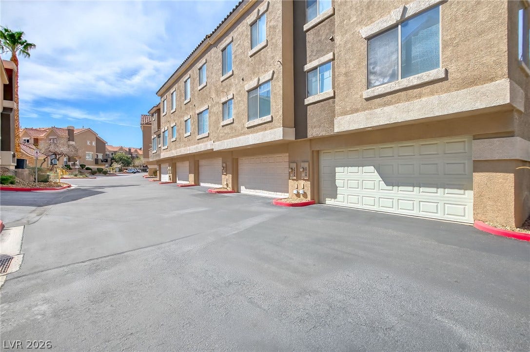 2752 Fountain Vista Lane, Henderson, NV 89074 Multi-level townhomes feature built-in garages beneath stucco exteriors and neat paved driveways.