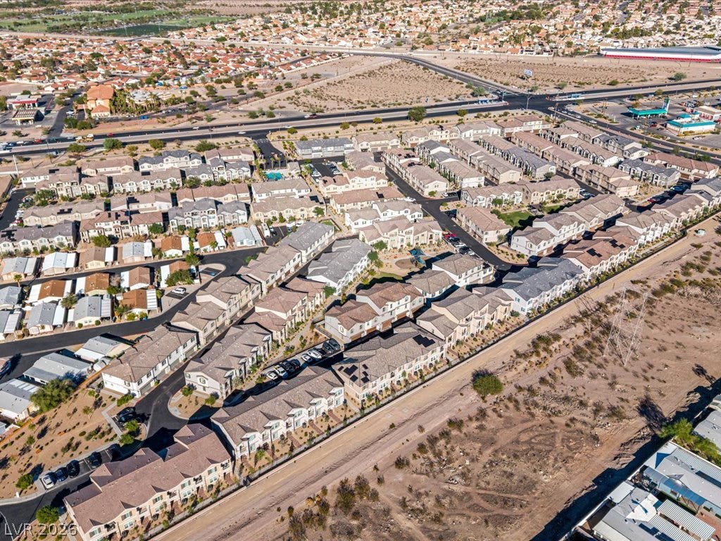 671 Foam Flower Lane, Henderson, NV 89015 An aerial perspective showcases a vibrant desert neighborhood of multi-level townhomes near open landscape.