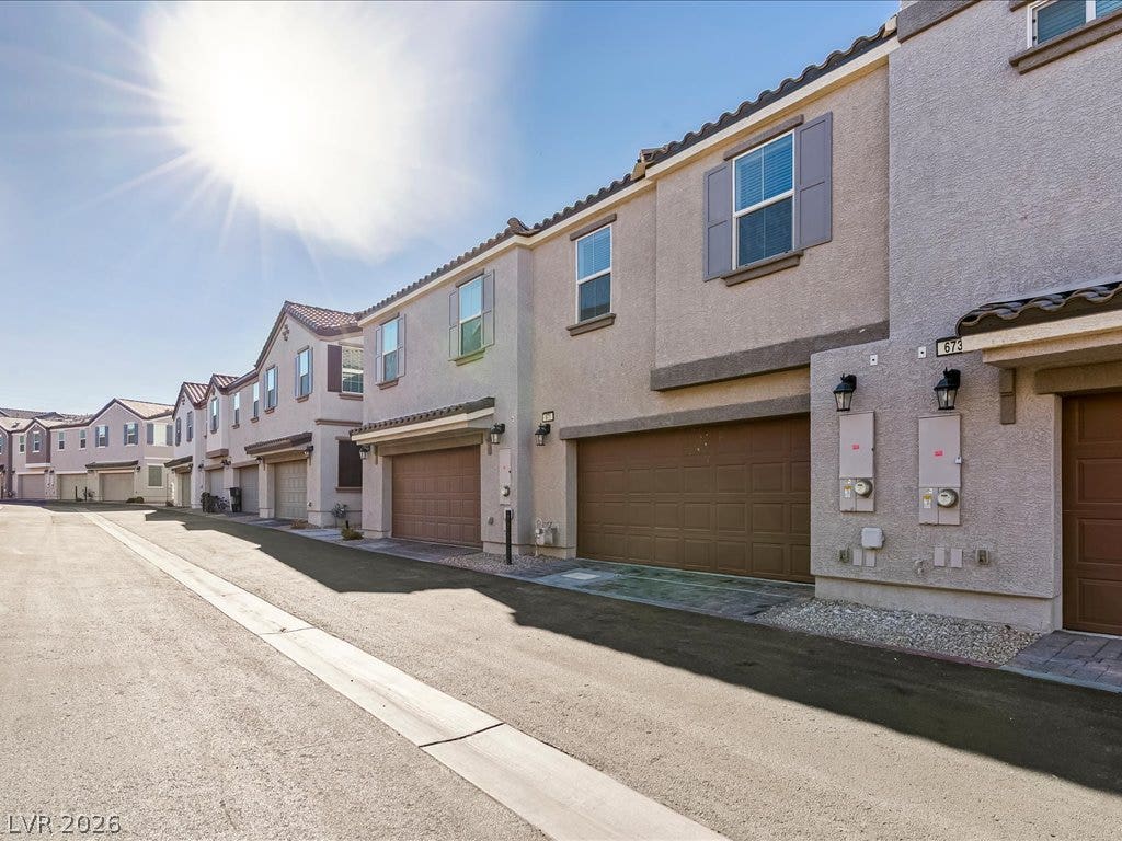 671 Foam Flower Lane, Henderson, NV 89015 Sunlight bathes this modern townhome exterior showcasing clean lines and multi-vehicle garage entries.