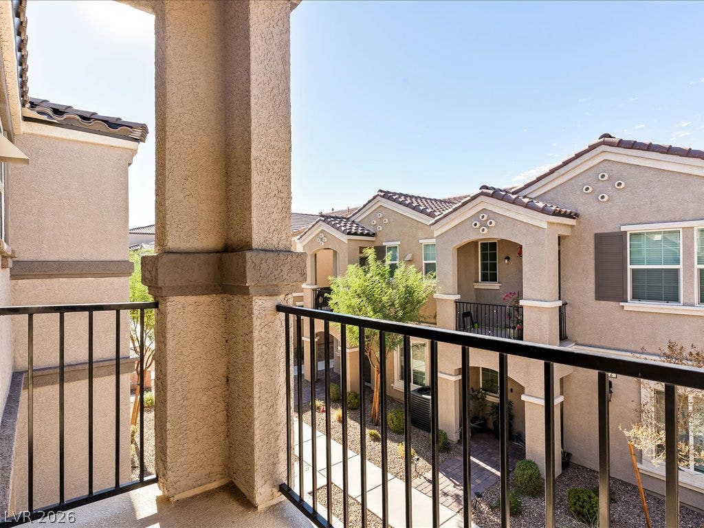 671 Foam Flower Lane, Henderson, NV 89015 An elevated private balcony overlooks a landscaped courtyard surrounded by multi-level residential structures.