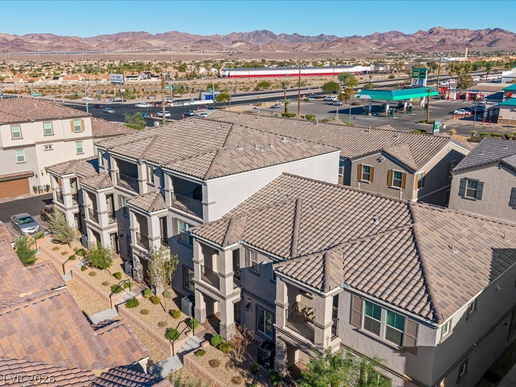 671 Foam Flower Lane, Henderson, NV 89015 Multi-level residential buildings feature Spanish tile roofing under a clear desert sky.