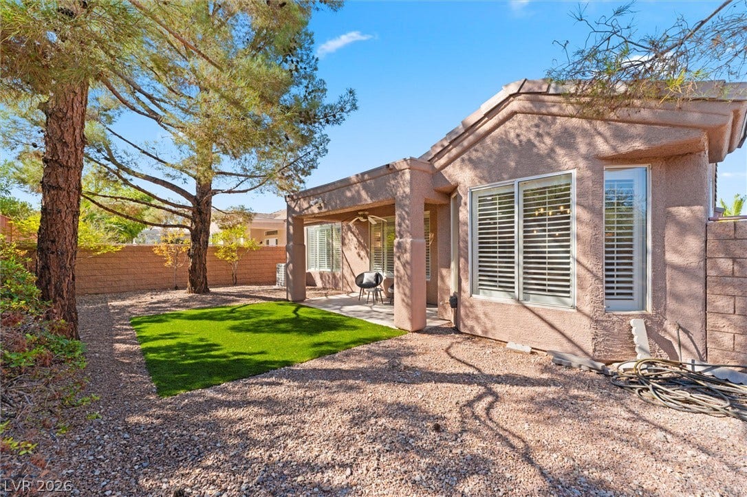 2163 Chapman Ranch Drive, Henderson, NV 89012 Mature trees shade a tidy gravel yard featuring a covered patio and patch of green lawn.