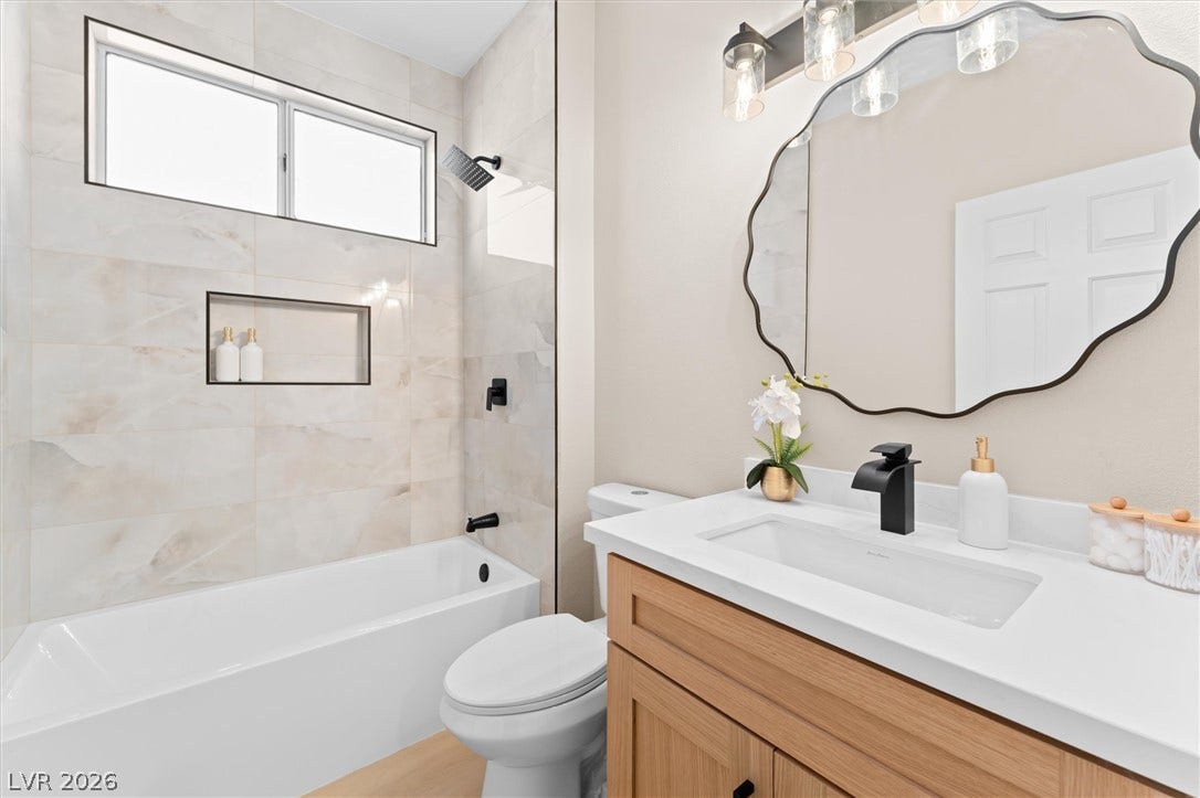 2163 Chapman Ranch Drive, Henderson, NV 89012 Tiled tub surround with a built-in niche and a light wood vanity complete this bathroom.