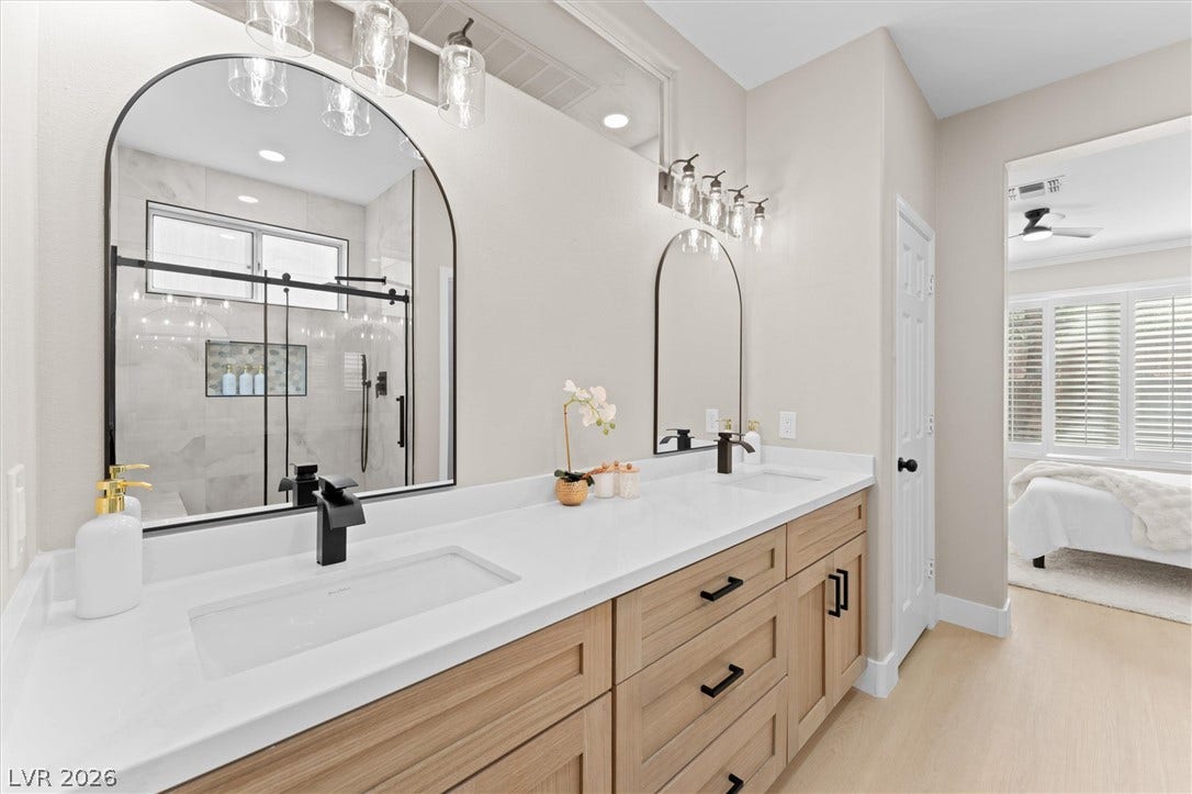 2163 Chapman Ranch Drive, Henderson, NV 89012 Double vanity sinks and clean lines elevate this master bathroom with light wood cabinetry.