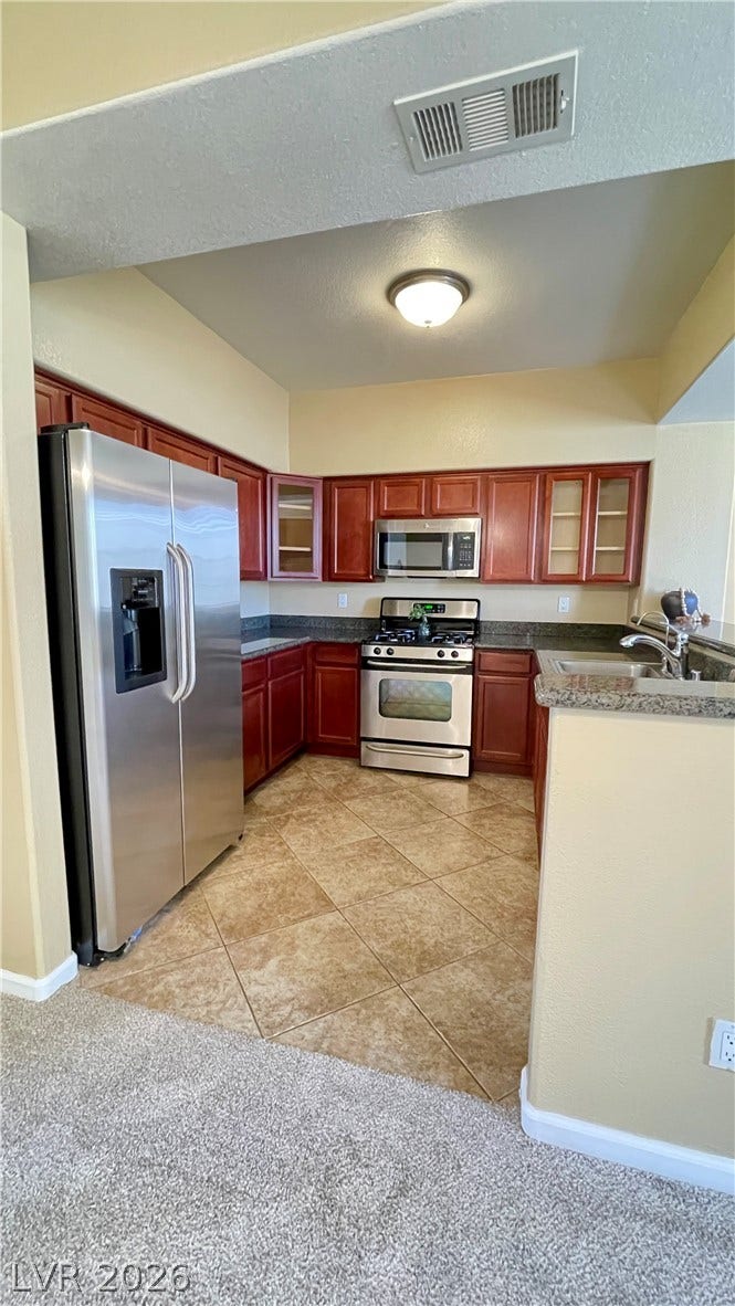 1617 Queen Victoria Street, #201, Las Vegas, NV 89144 Rich wood cabinetry and stone counters define this well-appointed kitchen space.
