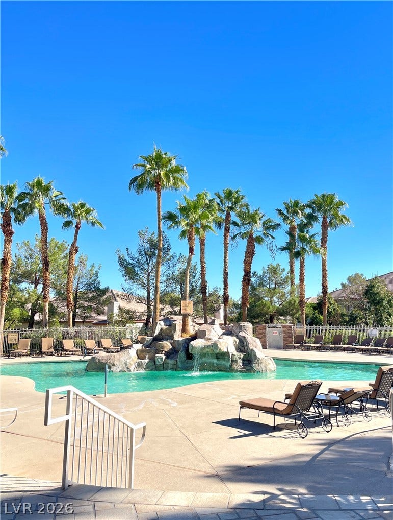 1617 Queen Victoria Street, #201, Las Vegas, NV 89144 Palm trees surround a resort-style swimming pool featuring a rock waterfall and sunbathing deck.