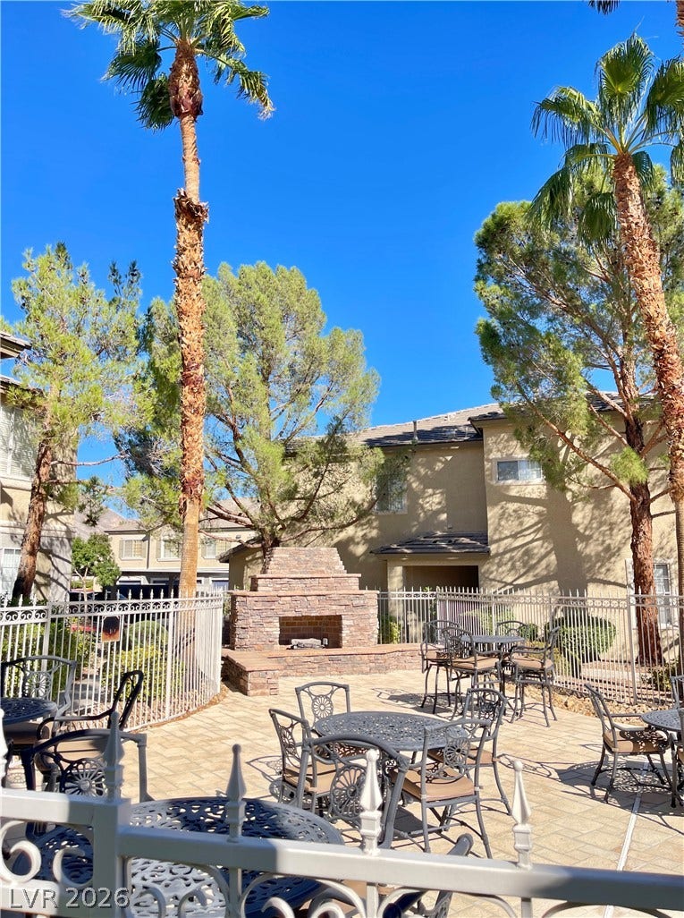 1617 Queen Victoria Street, #201, Las Vegas, NV 89144 A spacious paved pool side gathering space features a stone fireplace set against a backdrop of mature trees.