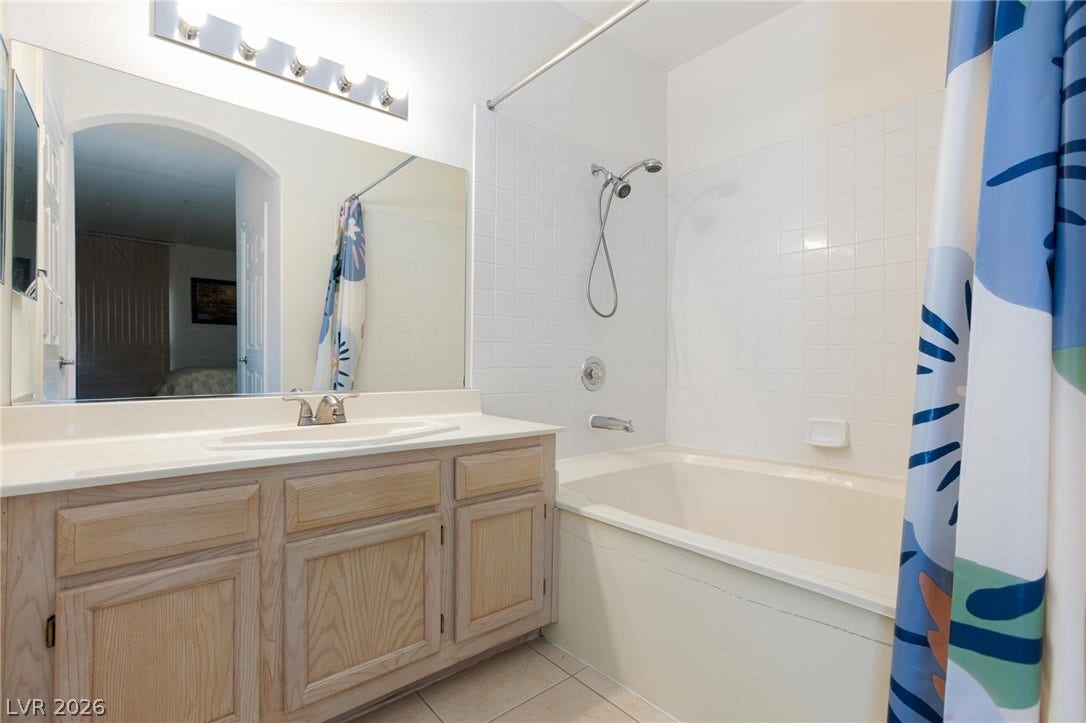 Warm wood cabinetry pairs with neutral tile flooring in this classic bathroom design.
