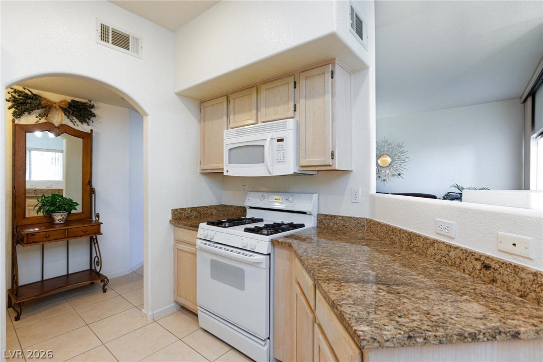 Granite countertops and classic cabinetry accent this functional cooking space with tiled flooring.