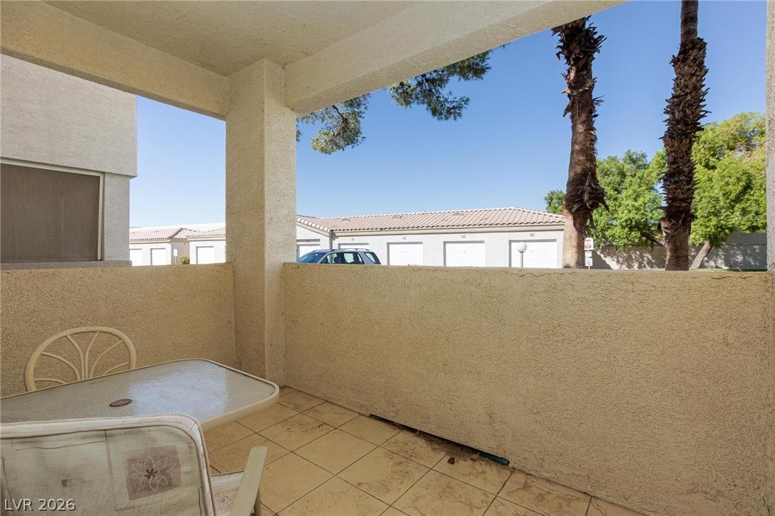 A covered tiled patio looks out toward neighborhood views framed by soaring palm trees.