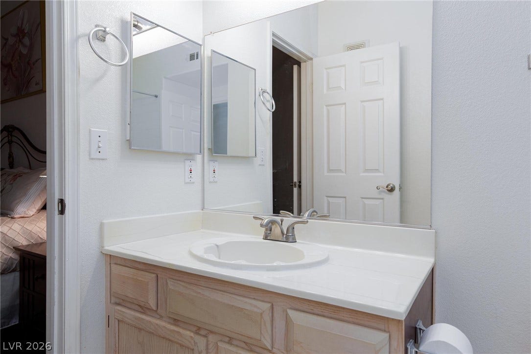 A light wood vanity paired with a wide mirror enhances this functional bathroom space.