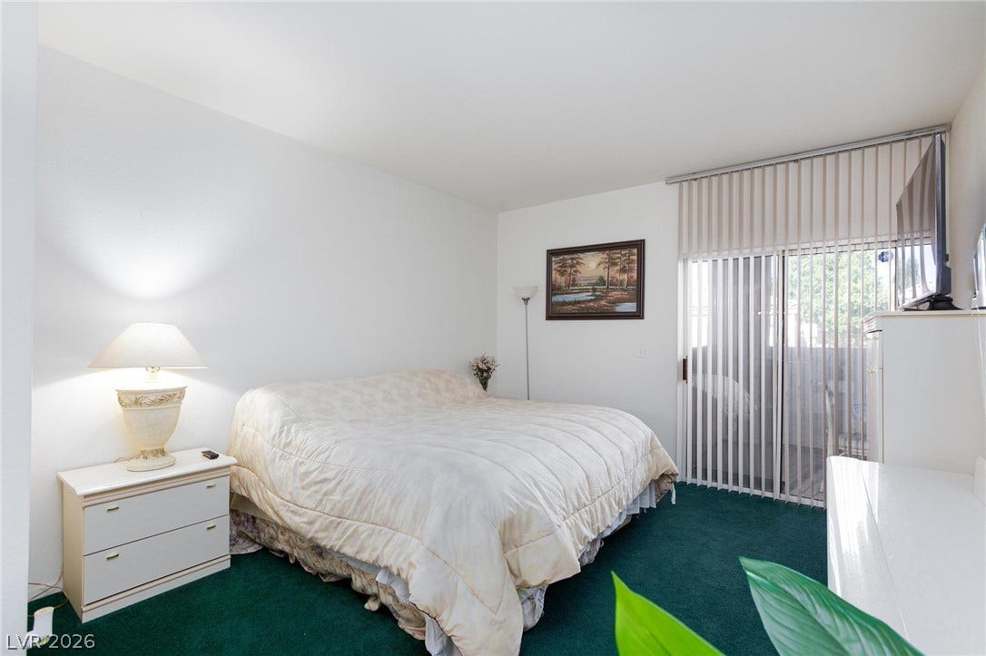 Sliding doors open to a private balcony from this bedroom with wall-to-wall carpeting.