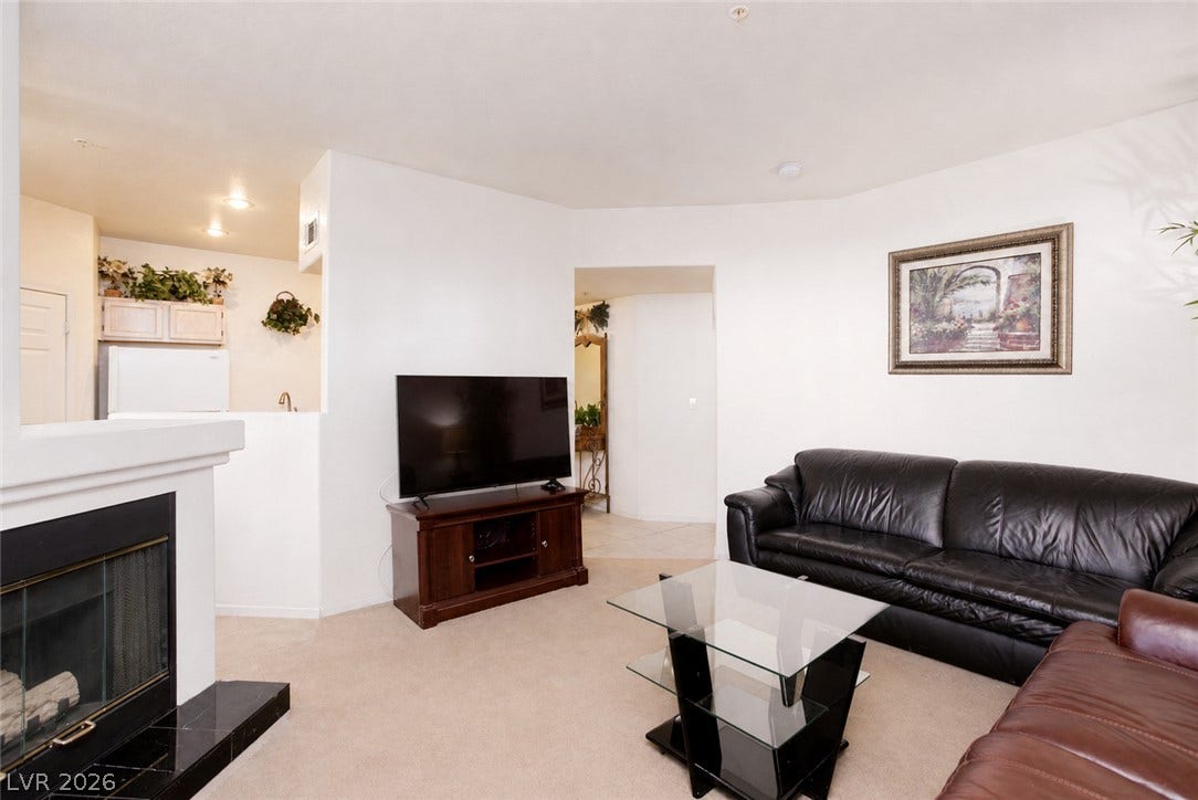 An inviting fireplace and open sightlines to the kitchen highlight this comfortable living area.