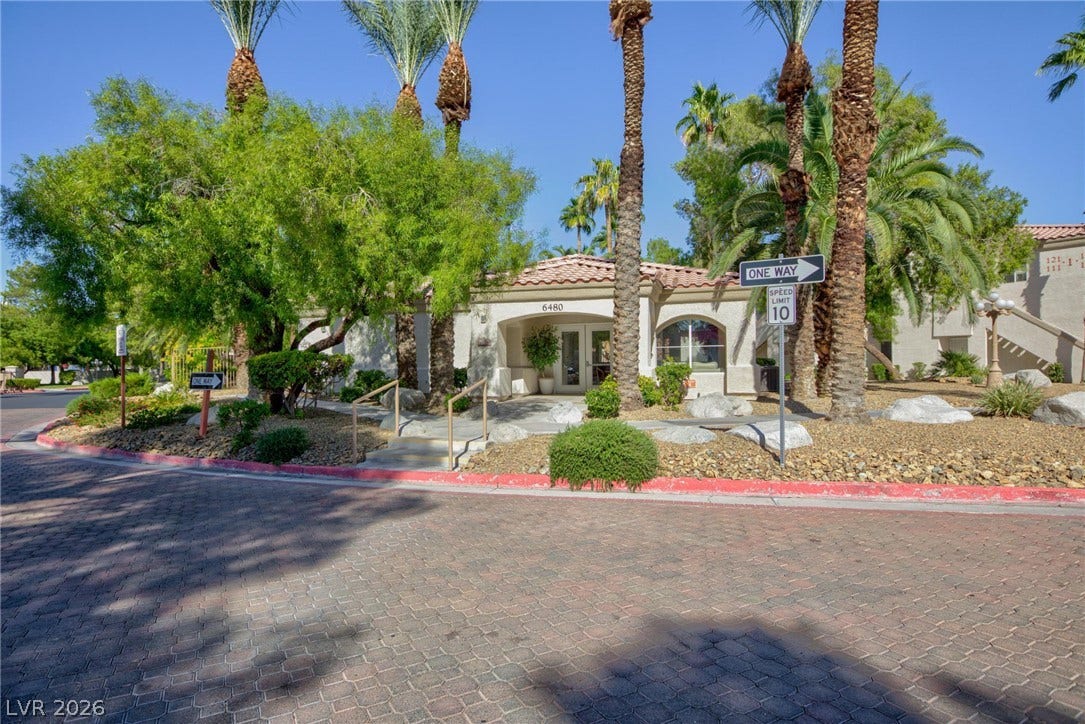 Lush palms and manicured desert landscaping frame the welcoming exterior entry of this Spanish-style structure.
