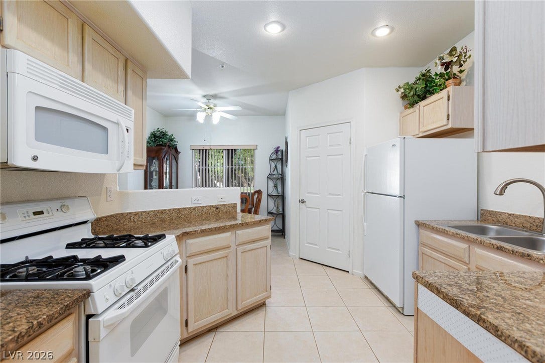 Granite counters and neutral tile flooring anchor this functional, well-lit kitchen layout.