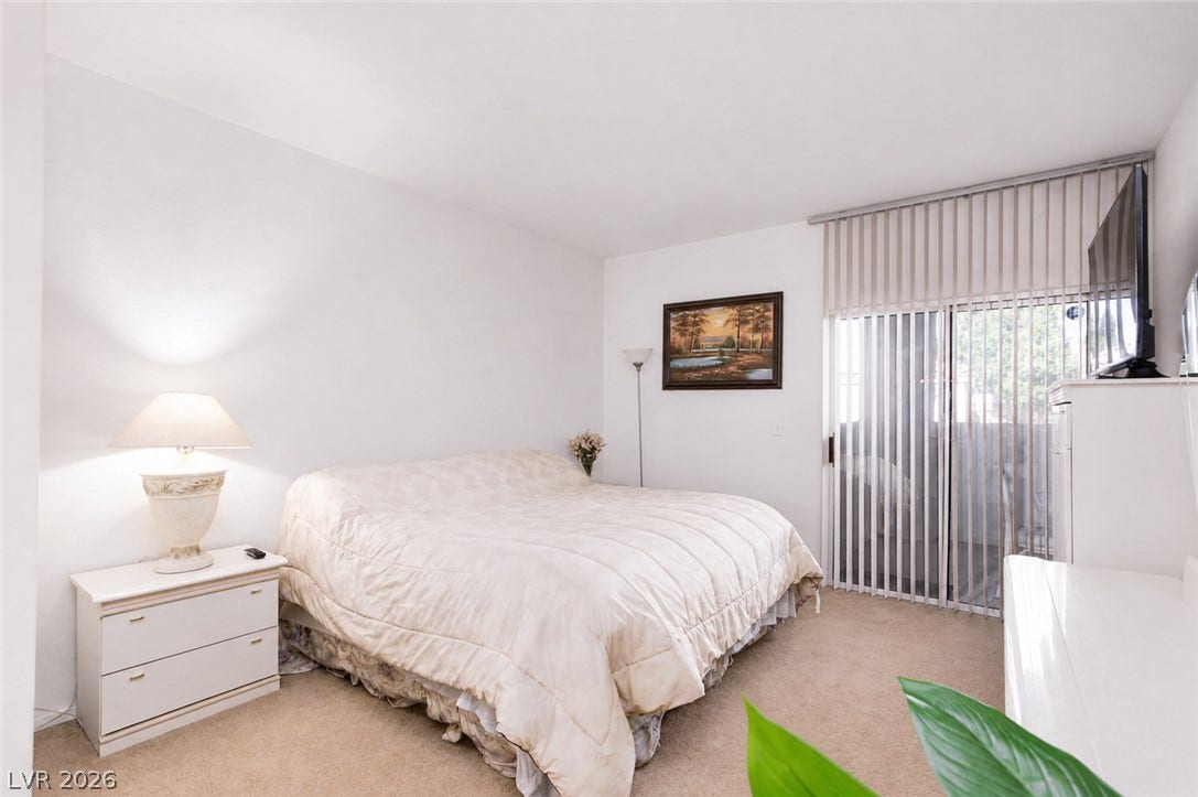 Sliding glass doors open directly to the outdoors from this carpeted bedroom.