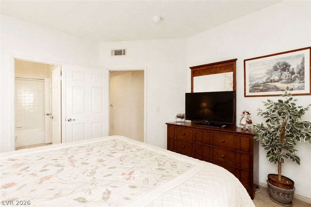 An en-suite bathroom connects seamlessly to this restful bedroom featuring carpeted floors.