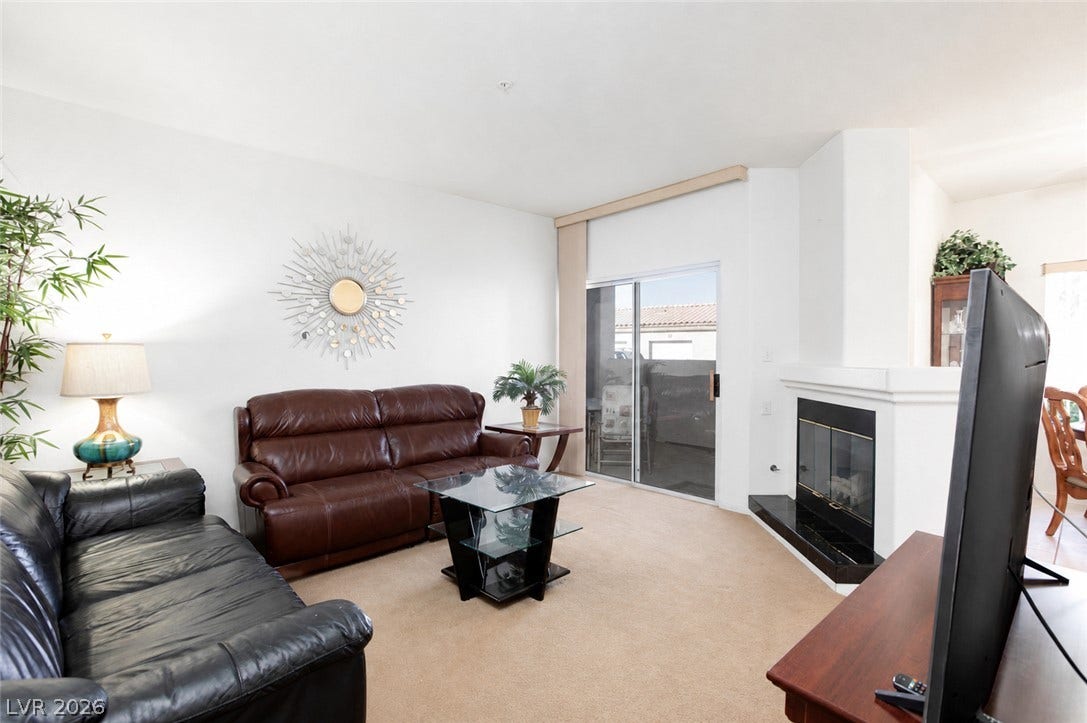 Sliding glass doors open to the outdoors from this inviting living area featuring a fireplace.