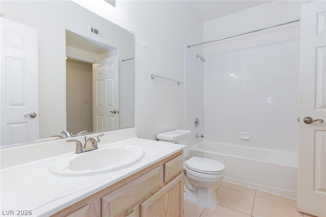 Tiled flooring and a classic vanity with a large mirror highlight this functional space.