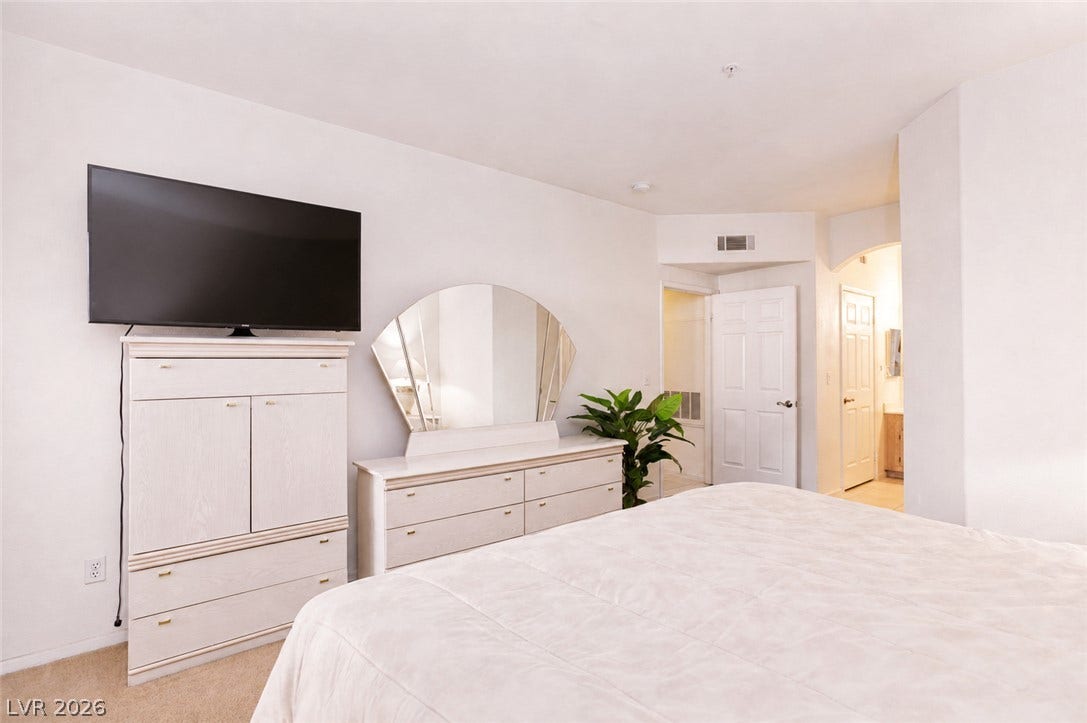 Plush carpeting and crisp white walls create a serene and restful bedroom atmosphere.