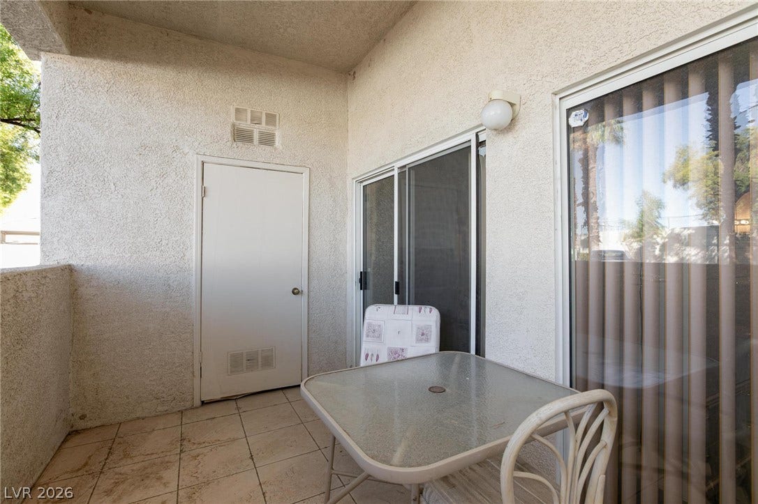 Tiled flooring and stucco walls define this private covered outdoor patio space.