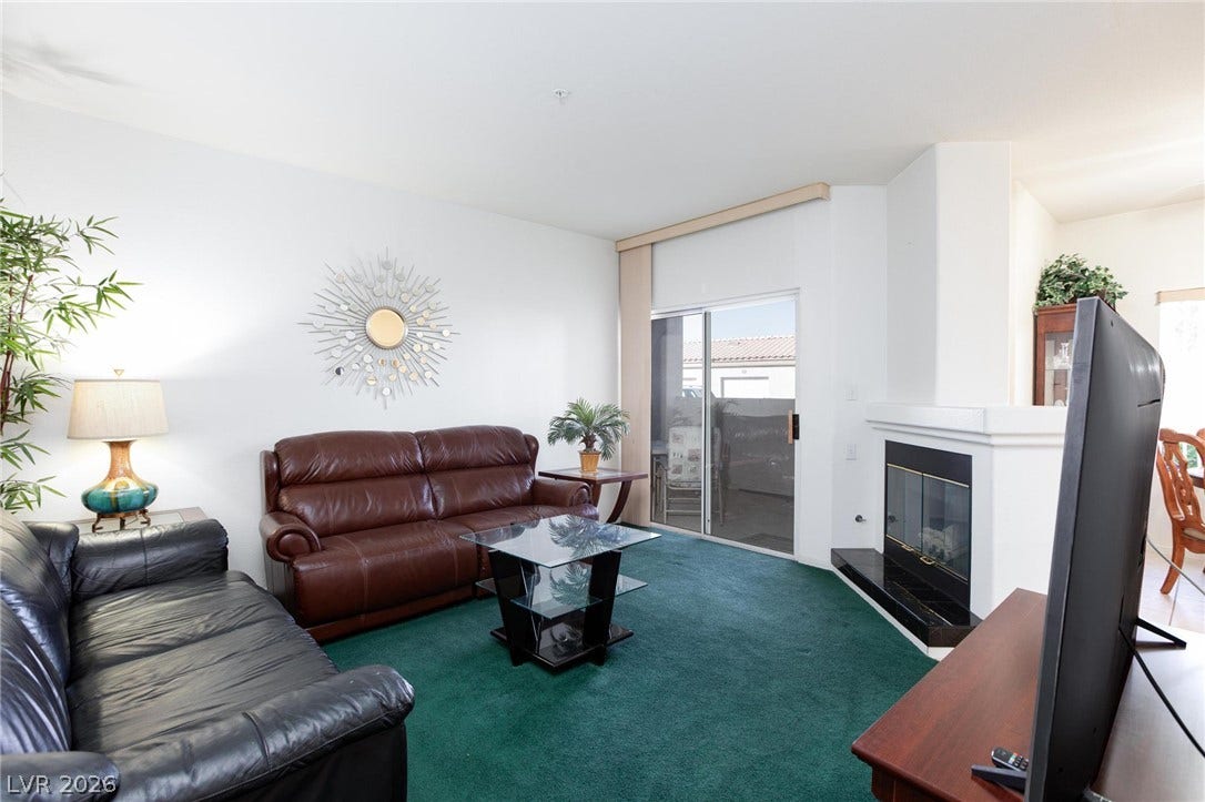 Sliding glass doors open to the patio from this inviting living area featuring a fireplace.