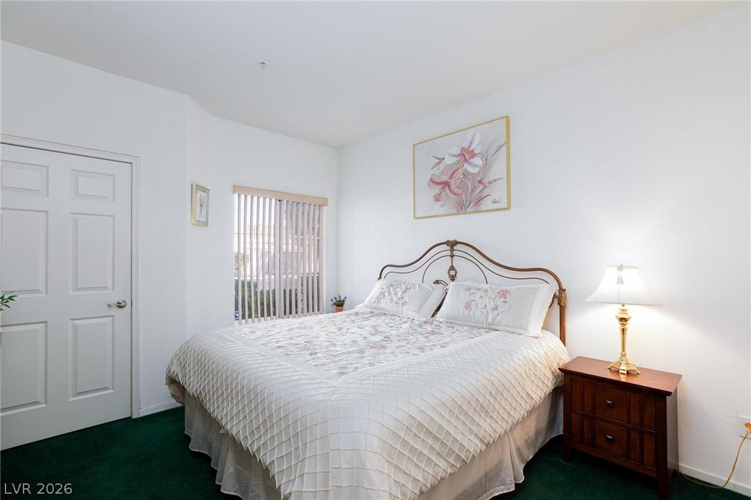 Richly colored carpeting anchors a restful bedroom with smooth white walls and classic panel doors.