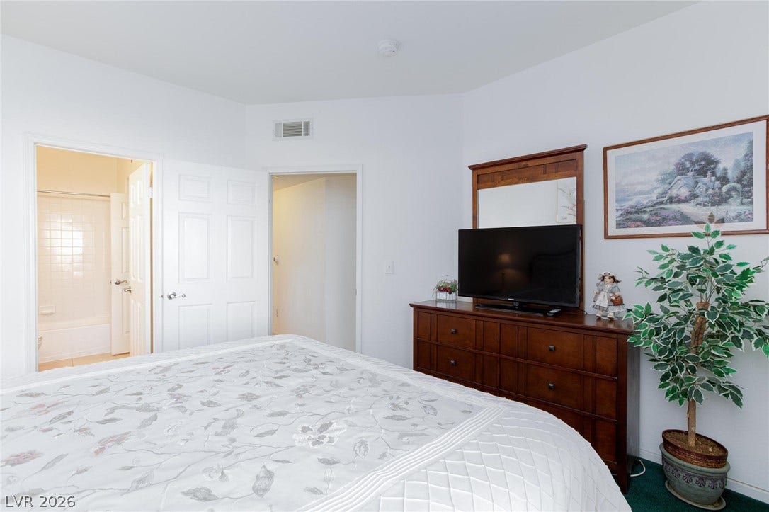 An inviting carpeted bedroom connects directly to an en suite bathroom.