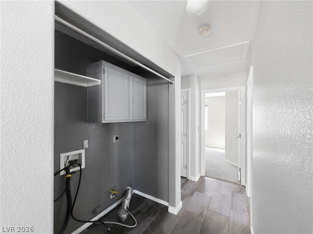 A dedicated laundry alcove features built-in cabinetry and durable flooring near the hallway.