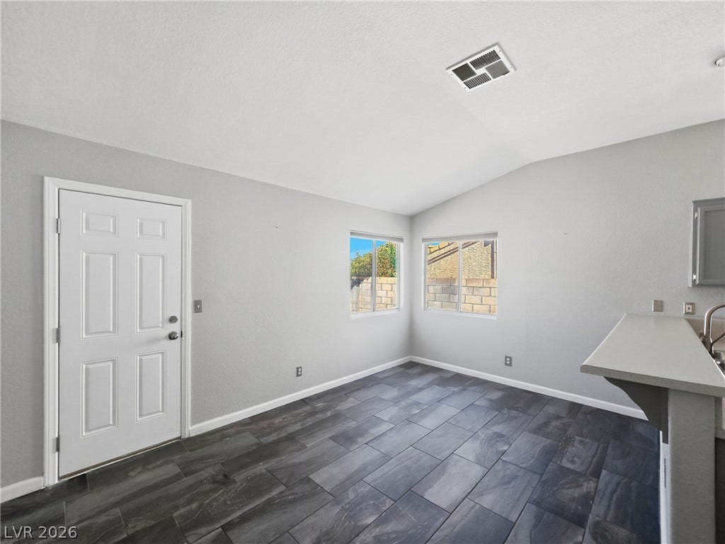 Dark tile flooring and vaulted ceilings create a modern backdrop for this versatile dining area.