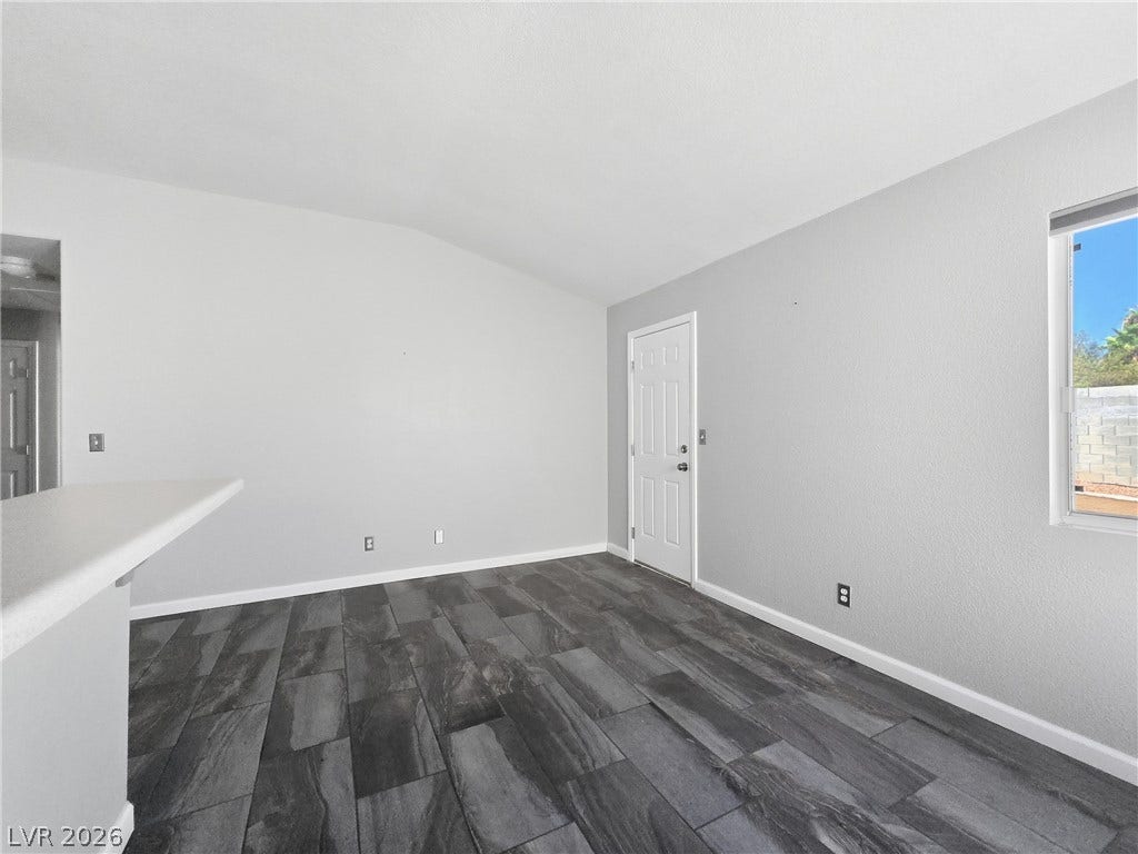 Striking dark-toned tile flooring anchors this open living space beneath a vaulted ceiling.
