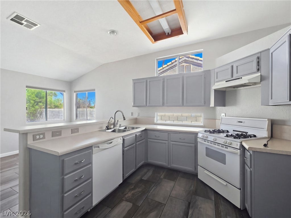 High vaulted ceilings and ample cabinetry define this functional, light-filled kitchen space.