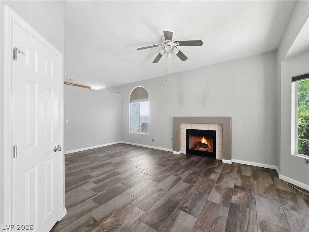 A classic wood-look tile floor complements the cozy fireplace in this inviting living space.