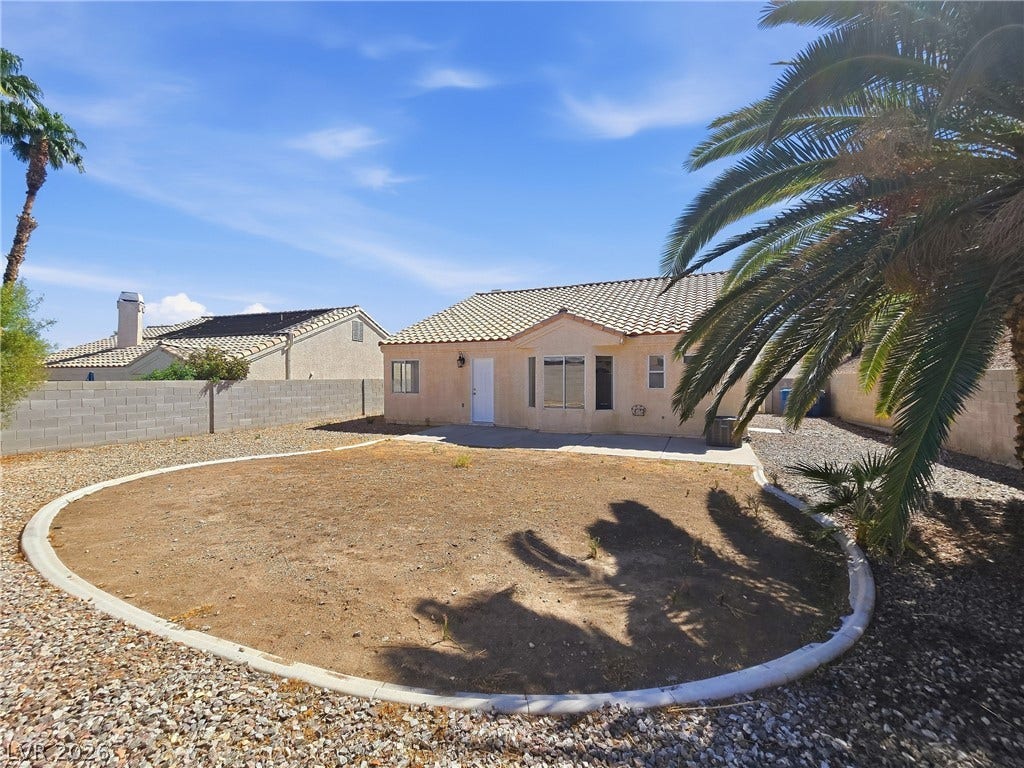 Palm trees frame a spacious, fenced backyard behind a classic tile-roof home.