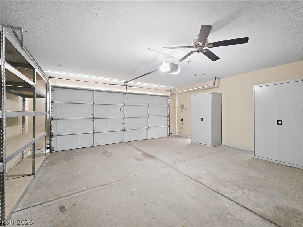 An organized two-car garage provides substantial storage options alongside a clean concrete floor.