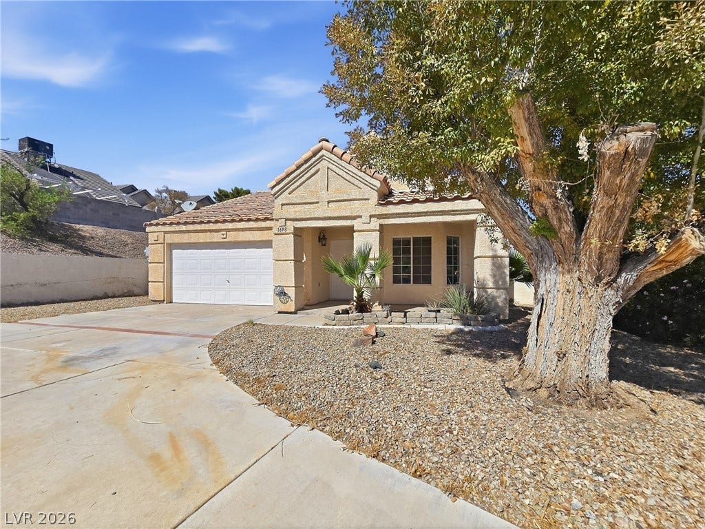 Classical tiled roofing and textured stucco walls define this desert-landscaped single-level home.