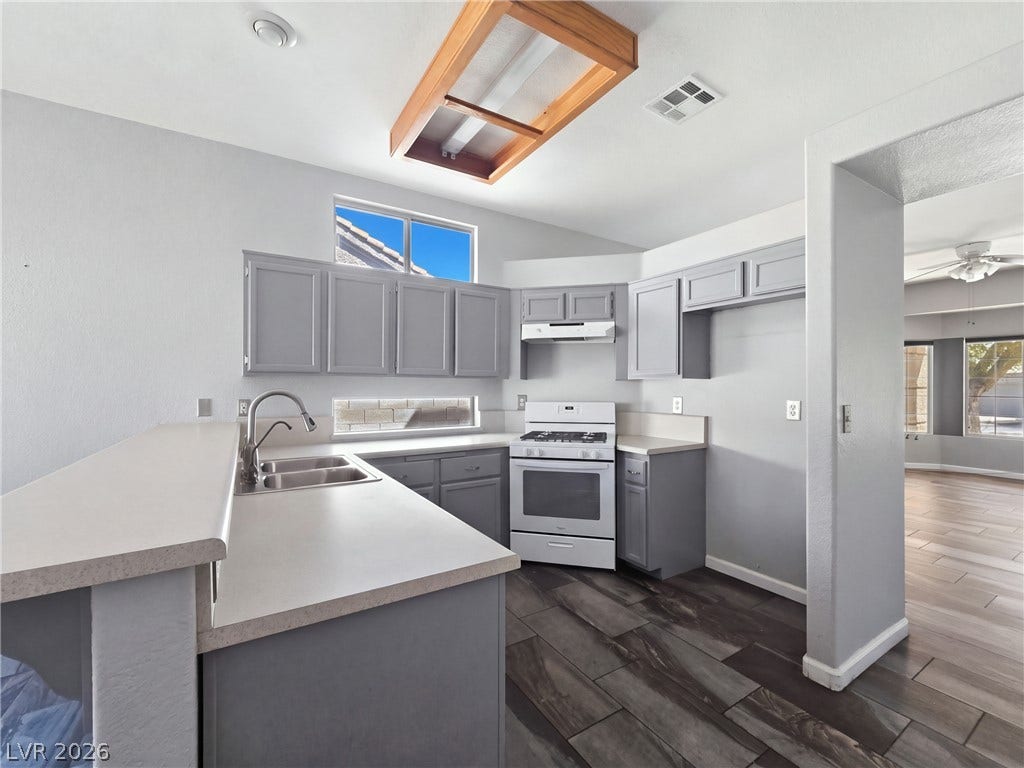 Dark plank flooring complements the functional u-shaped layout and raised breakfast bar.