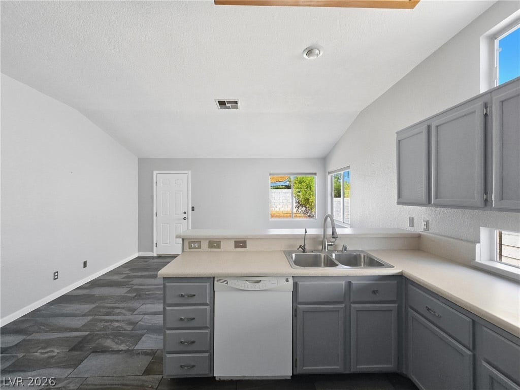 An open kitchen looks out over the adjacent living area with stone-look flooring.