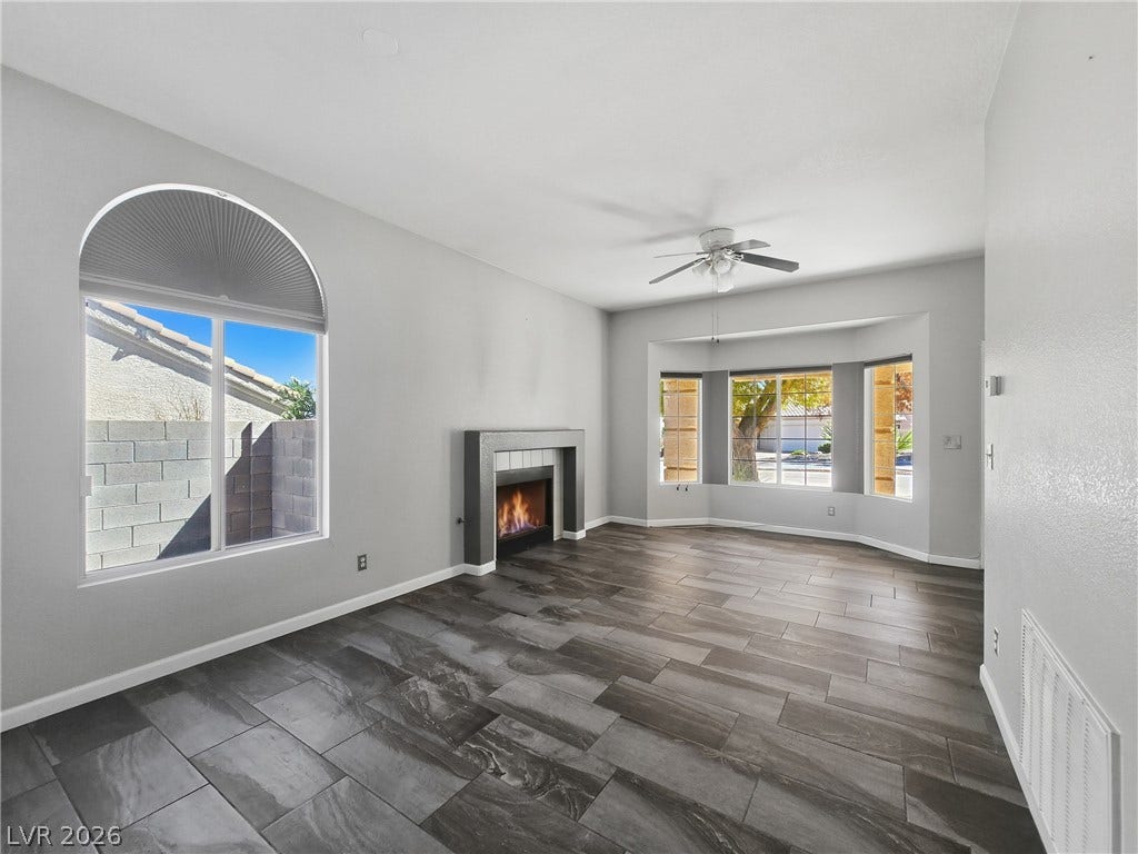 Plank-style tile floors and a modern fireplace anchor this sunlit, airy room.