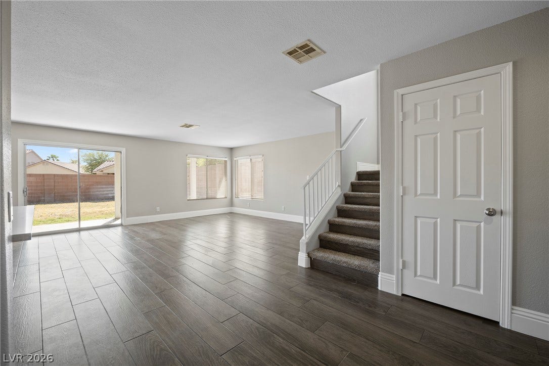 Plank flooring and a carpeted staircase anchor this open main living space.