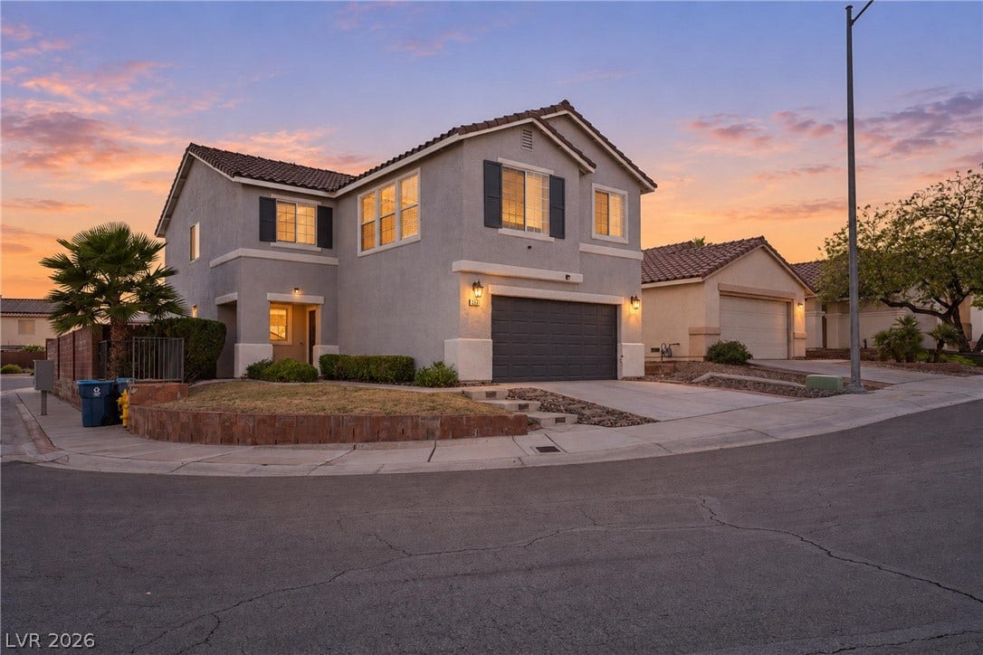 An inviting two-story stucco exterior showcases structured architectural lines against a dramatic sunset sky.