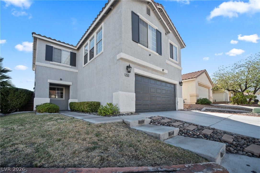 A classic stucco exterior features a spacious two-car garage and manicured path.
