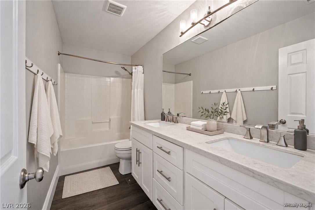 Double vanities with stone counters and modern fixtures anchor this refreshed bath space.