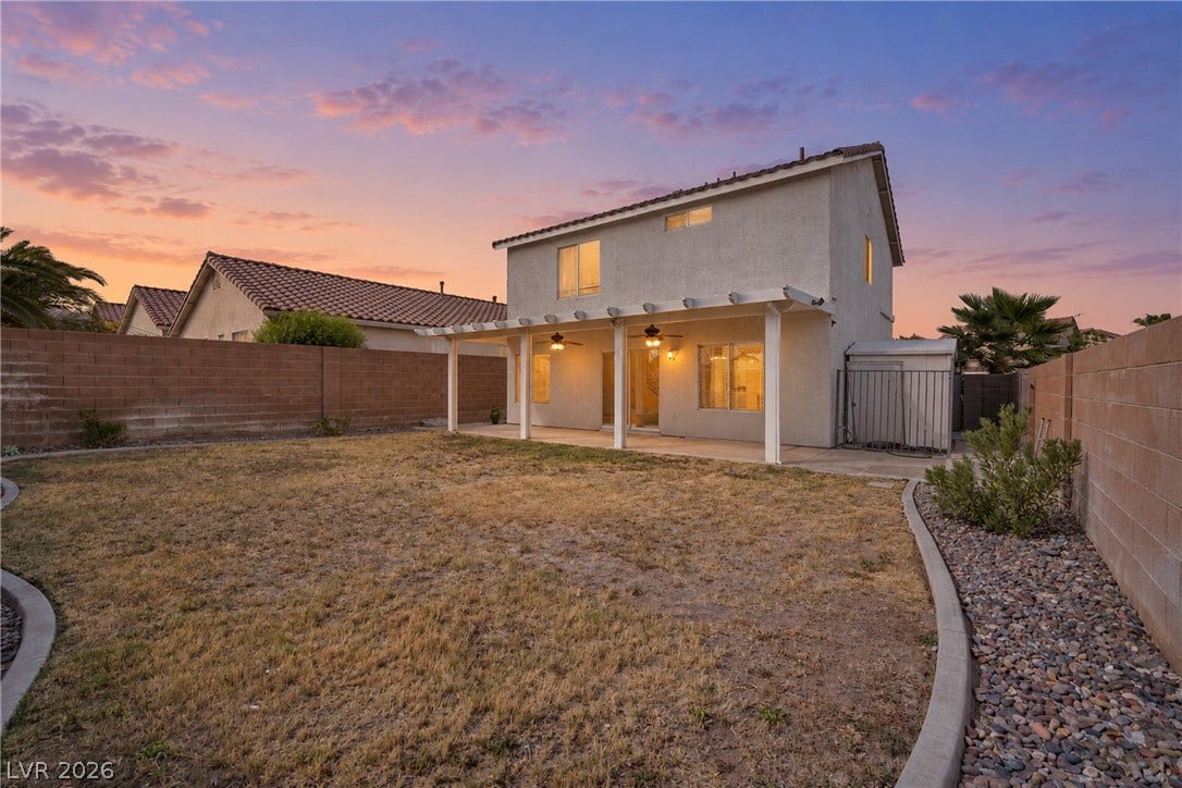 A spacious backyard is enclosed by block walls and features a covered patio area.