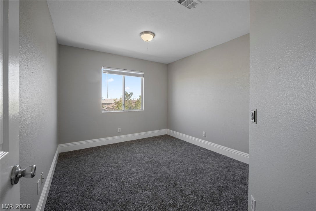Plush carpet and a window highlighting natural light define this versatile room.
