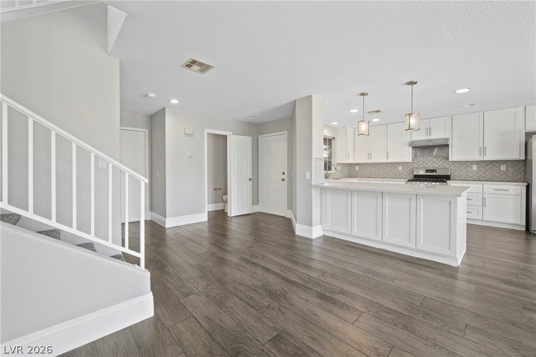 Plank flooring anchors the open-concept layout connecting the main living space to the kitchen.