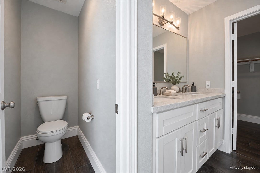 Clean lines and stone countertops elevate this modern bathroom featuring a separate water closet.